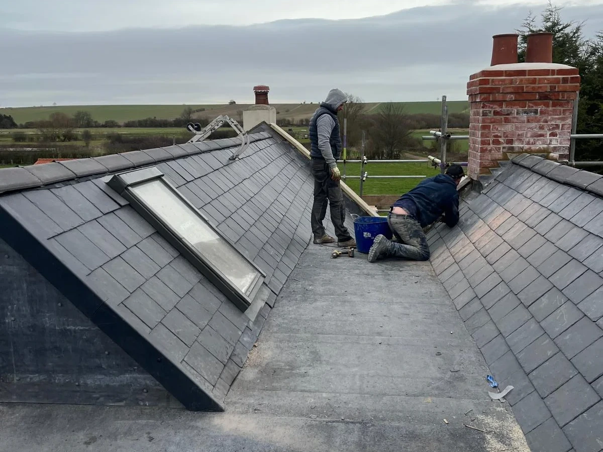 Team working along the valley between slate roof slopes