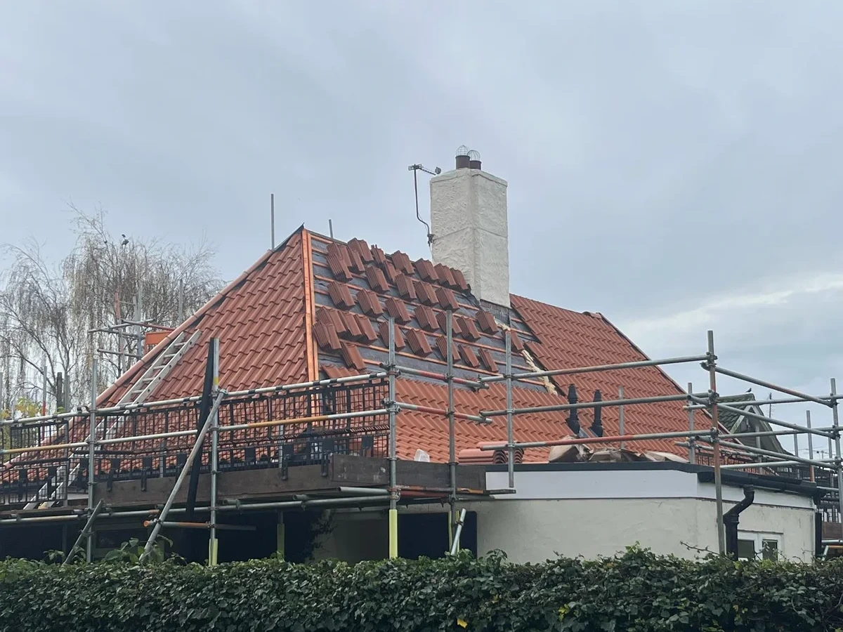 Red tiled roof and chimney surrounded by scaffolding