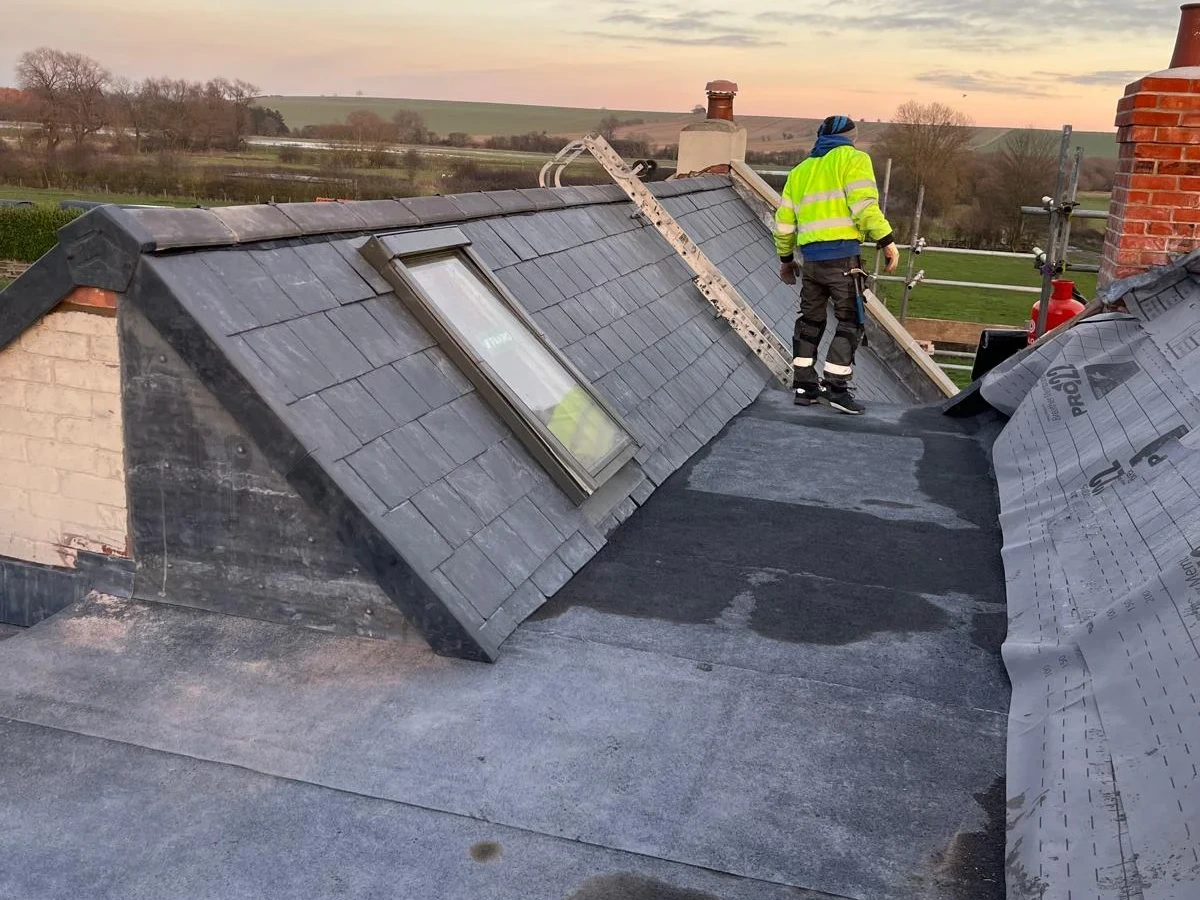 Roofing work beside a roof window and slate slope