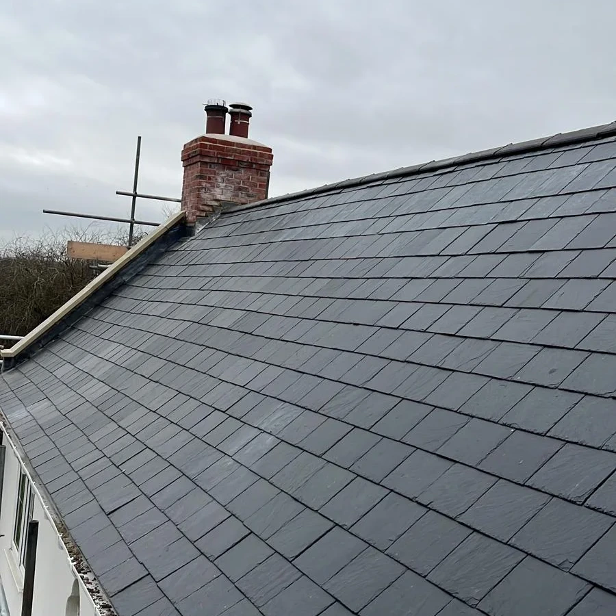 Broad slate roof slope with chimney and scaffold access
