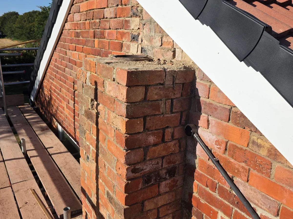 Brick chimney on a tiled roof beside the gable edge
