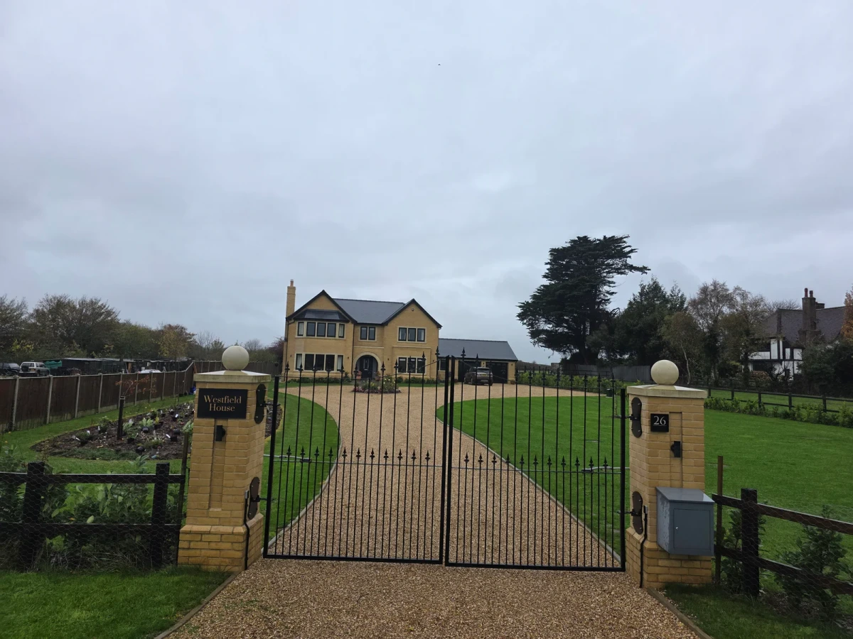 Driveway entrance and gates leading to a detached house