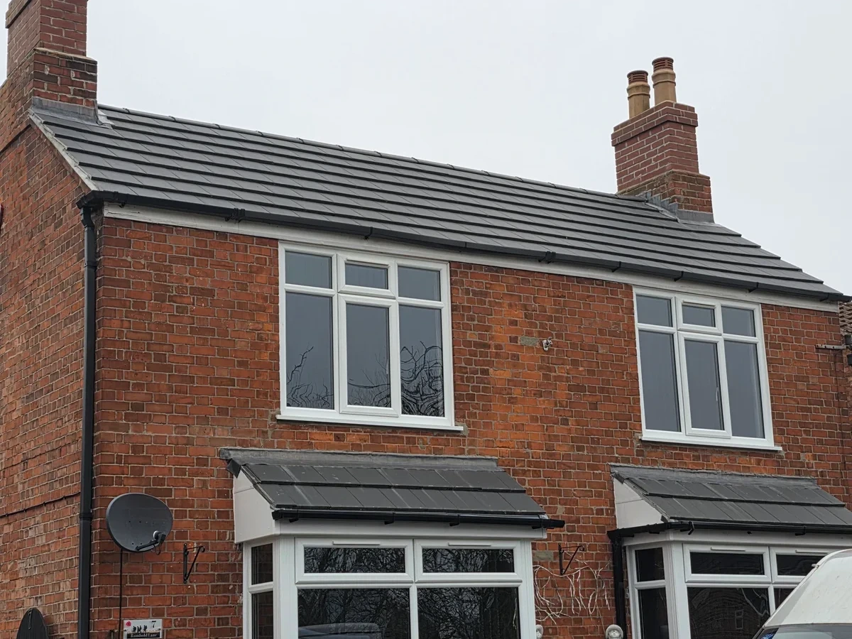 Tiled roof and twin chimneys above a brick house