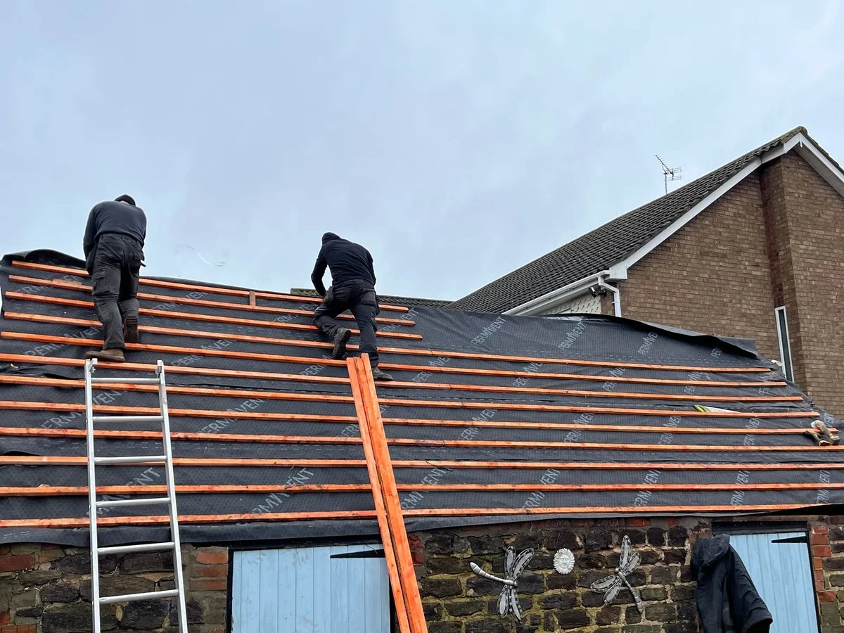 Roof battens being fitted above a brick outbuilding