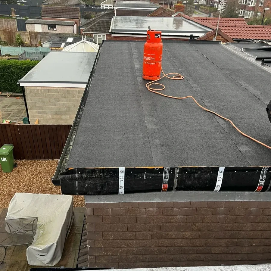 Flat roofing in progress with tools on the roof surface